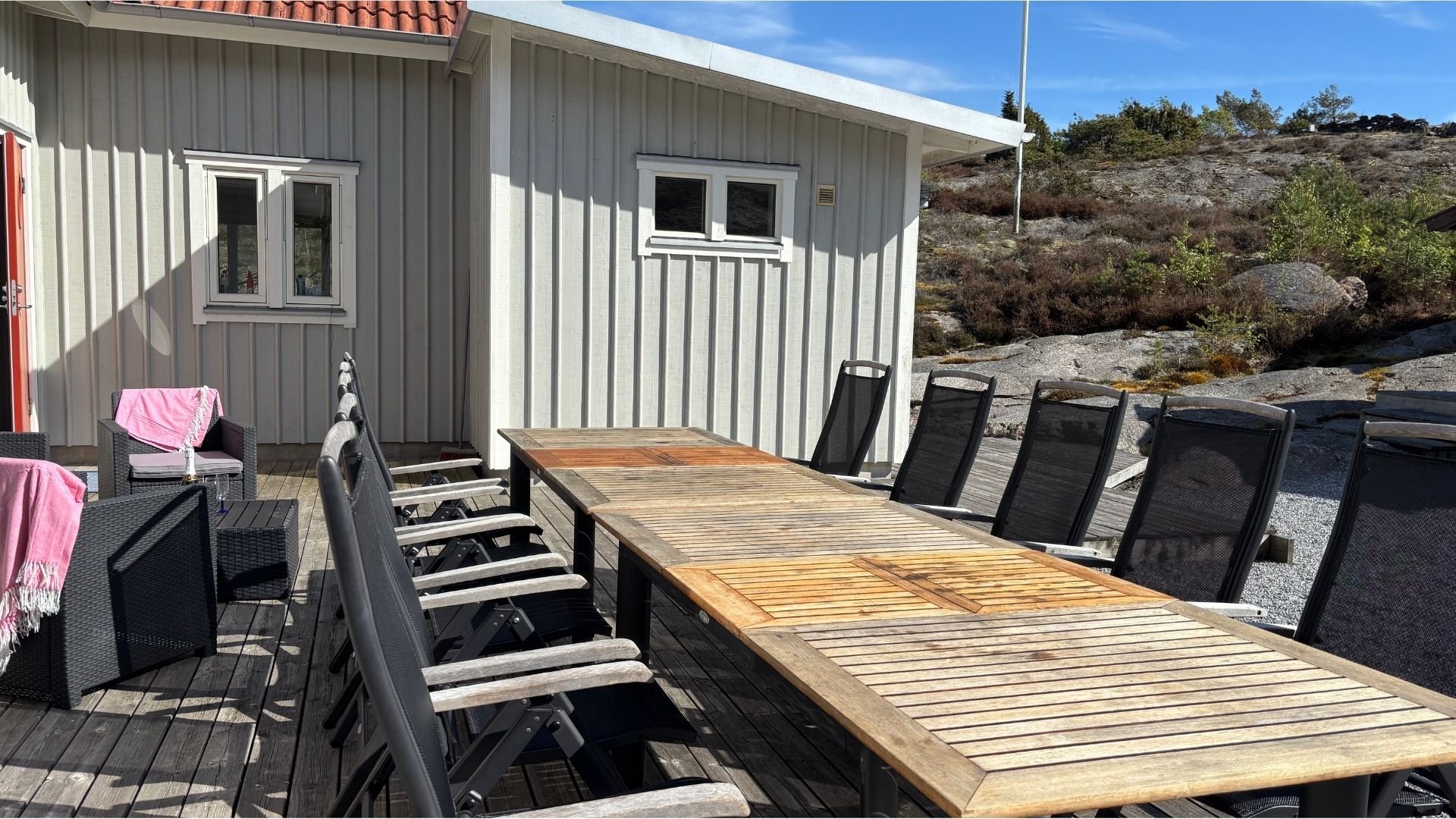 Stor uteplats med långt matbord och stolar på trädäck vid Apelgården 81 på Tjörn