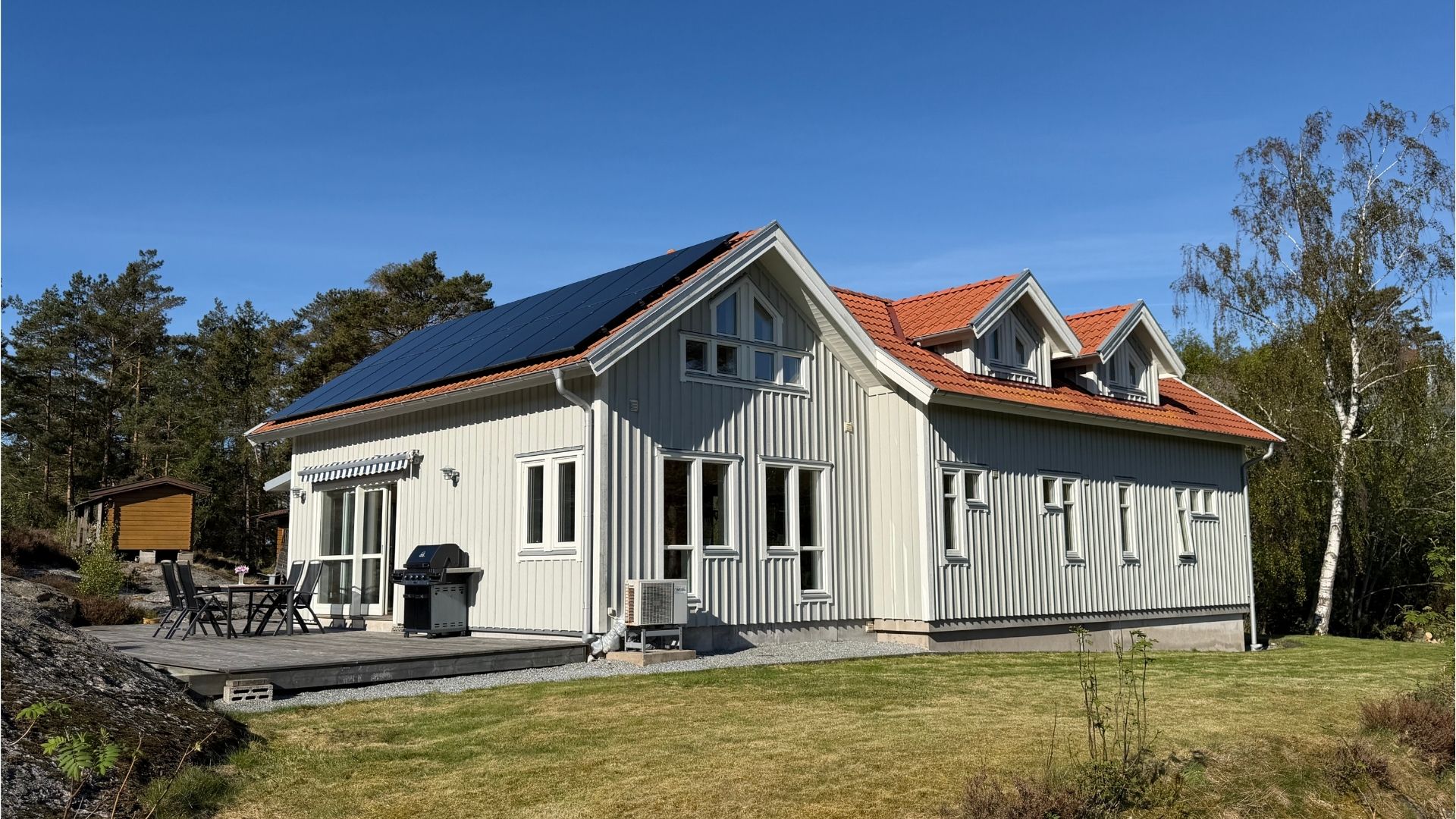 Apelgården 81 på Tjörn med altan, solceller och gräsmatta i sommarmiljö.